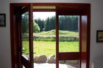 an open door with a view of a field at Merrick Cottage in Bargrennan