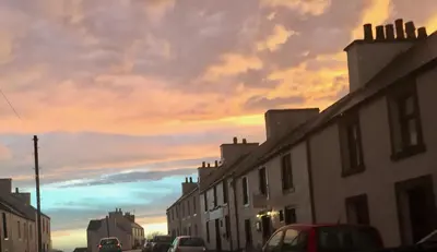 a city street with buildings and a cloudy sky at Lochindaal Hotel in Port Charlotte