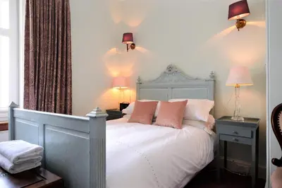 a bedroom with a white bed with pink pillows at Kimberley Apartment in Dunoon