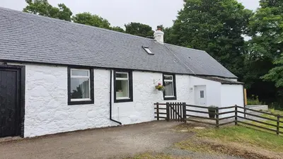 a white building with a cat sitting on top of it at Dairy Cottage with sea views in Girvan