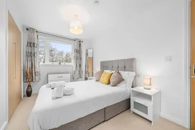 a white bedroom with a large bed and a window at Saughton Suite with views of Water of Leith in Edinburgh