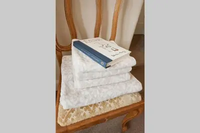 a stack of towels on a chair with a book at Troon Arts & Crafts Period Home Golf Beach in Troon