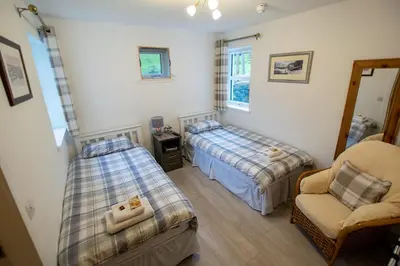 a bedroom with two beds and a chair in it at Corran Bunkhouse in Onich