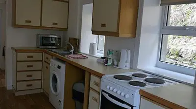 a kitchen with a stove top oven next to a window at Keeper's Cottage in Lochgilphead