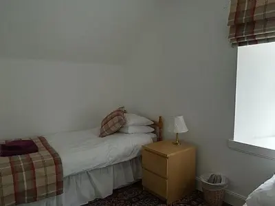 a bedroom with a bed and a table with a lamp at Keeper's Cottage in Lochgilphead