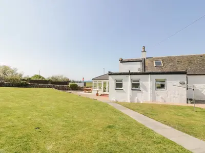 a white house with a grassy yard in front of it at Ailsa Shores in Turnberry