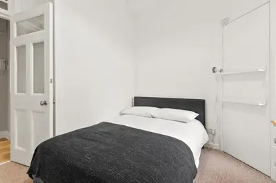 a white bedroom with a bed with a black blanket at Bay Apartment in Helensburgh