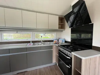 a kitchen with white cabinets and a black stove top oven at Pirnie Lodge Holiday Lets in Slamannan