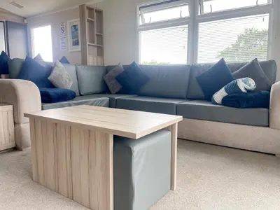 a living room with a blue couch and a table at Pirnie Lodge Holiday Lets in Slamannan