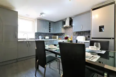 a kitchen with blue cabinets and a table and chairs at Signature - Kirkhill Lower in Kirkmuirhill