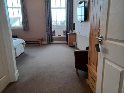a bedroom with a bed and a door with a room with windows at Grammar Lodge Guest House in Campbeltown