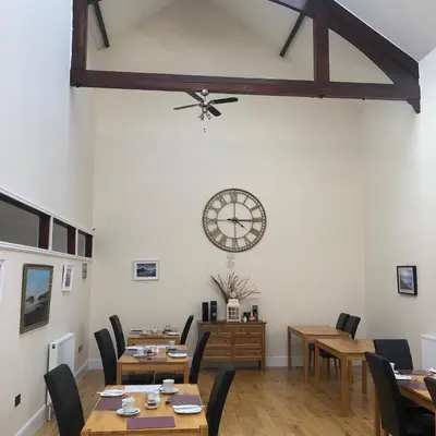 a dining room with tables and a clock on the wall at Grammar Lodge Guest House in Campbeltown