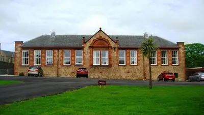 a large brick building with a palm tree in front of it at Grammar Lodge Guest House in Campbeltown