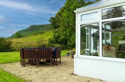 a table and chairs sitting outside of a house at Killean Farmhouse B&B in Inveraray
