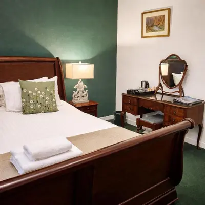 a bedroom with a bed and a desk with a mirror at Killean Farmhouse B&B in Inveraray