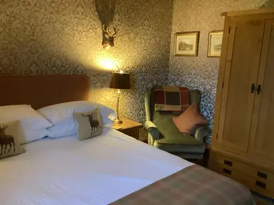 a bedroom with a large bed and a chair at Auchenlea bed and breakfast in Coatbridge
