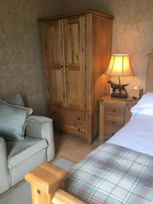 a bedroom with a bed and a chair and a cabinet at Auchenlea bed and breakfast in Coatbridge