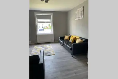 a living room with a black couch and a window at Beautiful two bedroom flat by the Loch in Balloch
