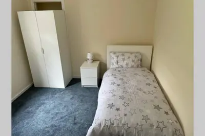 a small bedroom with a bed and a white cabinet at Beautiful two bedroom flat by the Loch in Balloch