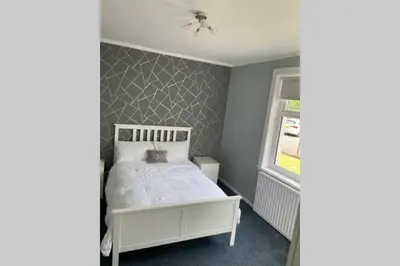 a bedroom with a white bed and a window at Beautiful two bedroom flat by the Loch in Balloch