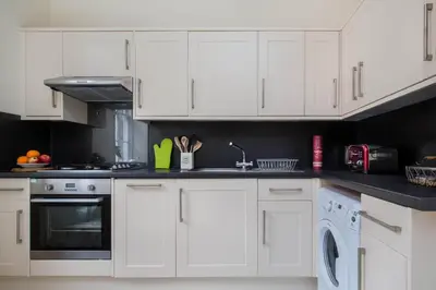 a white kitchen with white cabinets and a dishwasher at Stockbridge Two Bedroom Apartment in Edinburgh