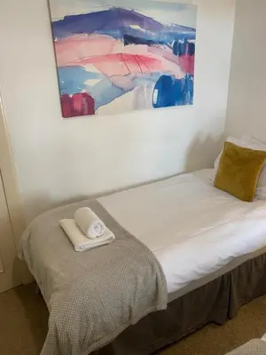 a bed in a room with a painting on the wall at Stockbridge Two Bedroom Apartment in Edinburgh