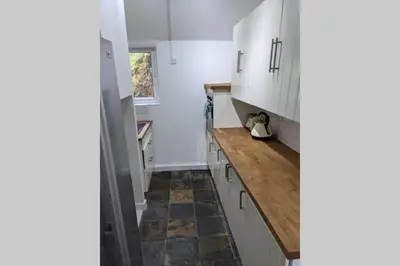 a kitchen with white cabinets and a wooden counter top at Glendyne Cottages, Highest Village in Scotland in Wanlockhead