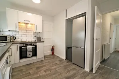 a kitchen with white cabinets and a stainless steel refrigerator at Signature - Caldercruix House in Caldercruix