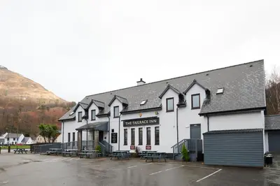 a white building with a parking lot in front of it at Tailrace Inn in Kinlochleven