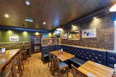 a dining room with wooden tables and blue booths at Tailrace Inn in Kinlochleven