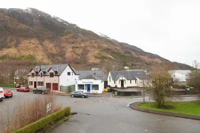 a group of houses in a parking lot next to a mountain at Tailrace Inn in Kinlochleven