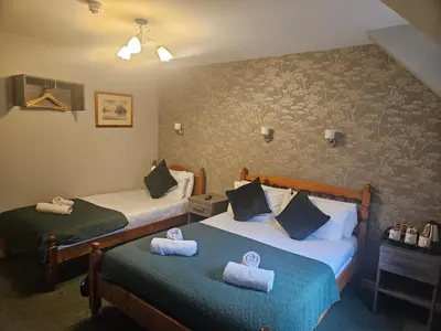two beds in a hotel room with towels on them at Tailrace Inn in Kinlochleven
