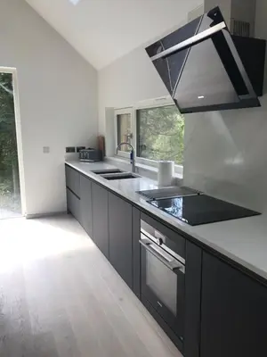 a kitchen with black cabinets and a sink at An Caisteal Lodge with cascading waterfall view in Crianlarich