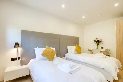 two beds in a bedroom with white sheets and yellow pillows at An Caisteal Lodge with cascading waterfall view in Crianlarich