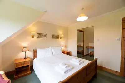 a bedroom with a large bed with towels on it at Capercaillie Cottage in Crianlarich