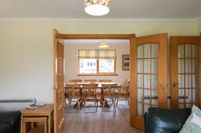a dining room with a table and chairs at Capercaillie Cottage in Crianlarich