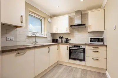 a kitchen with white cabinets and a window at Old Prestwick View - Donnini Apartments in Prestwick