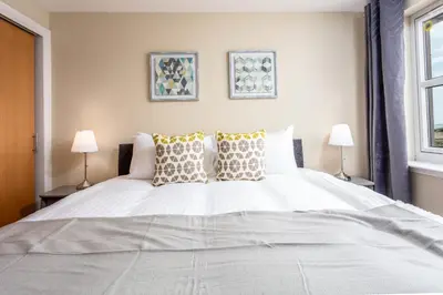 a bedroom with a large white bed with two lamps at Old Prestwick View - Donnini Apartments in Prestwick
