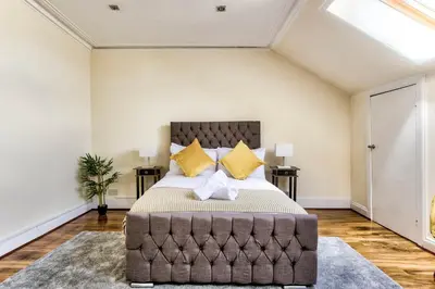 a bedroom with a large bed with yellow pillows at Stunning 5 bedroom apt, close to city centre, SEC, Hydro and motorway in Glasgow