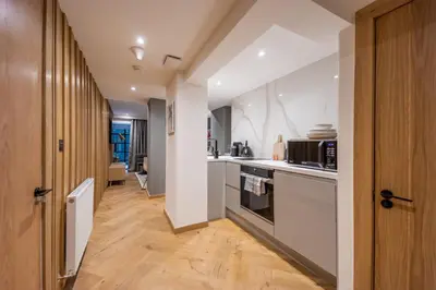 a kitchen with white appliances and a wooden floor at No1 Apartments Edinburgh - New Town in Edinburgh