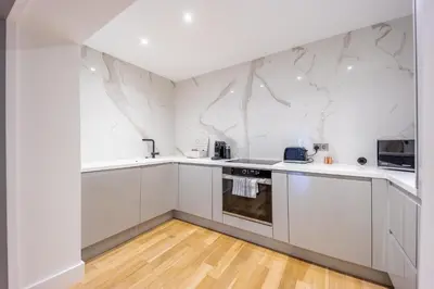 a white kitchen with white cabinets and a microwave at No1 Apartments Edinburgh - New Town in Edinburgh