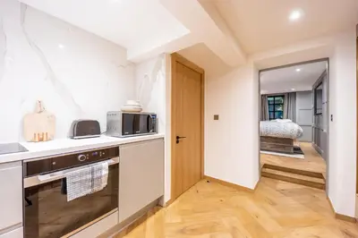 a kitchen with a stove and a door to a bedroom at No1 Apartments Edinburgh - New Town in Edinburgh
