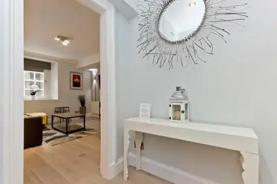 a living room with a white table and a mirror at Ultra Modern, West End Village, Refurbished basement appt in Edinburgh