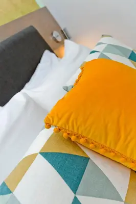 an orange pillow sitting on top of a bed at Ultra Modern, West End Village, Refurbished basement appt in Edinburgh