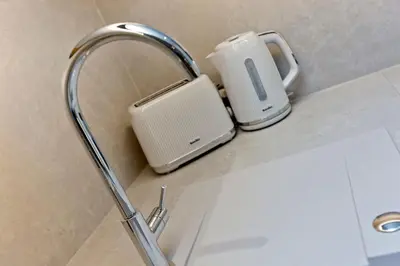 a sink with a faucet and a toaster on a counter at Ultra Modern, West End Village, Refurbished basement appt in Edinburgh
