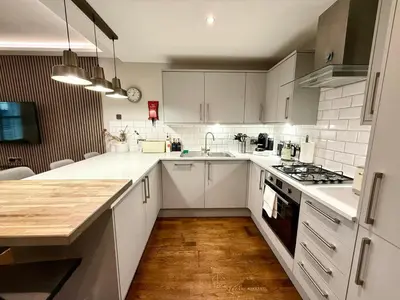 a kitchen with white cabinets and a wooden floor at Modern 3 Bedroom Apartment, West End in Edinburgh