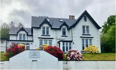 a white house with flowers in front of it at Glenorchy Lodge Hotel-Rooms Only in Dalmally