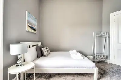 a white bedroom with a white bed and a lamp at Lothian Road - perfect city centre location. in Edinburgh