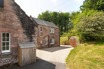 an external view of a brick building with a gate at Laundry Cottage: Drumlanrig Castle in Thornhill