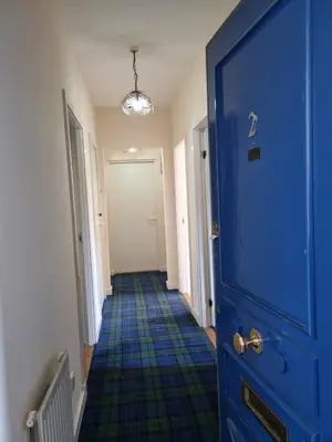 a hallway with a blue door and a blue floor at Carnarvon Street City Centre Apartment in Glasgow